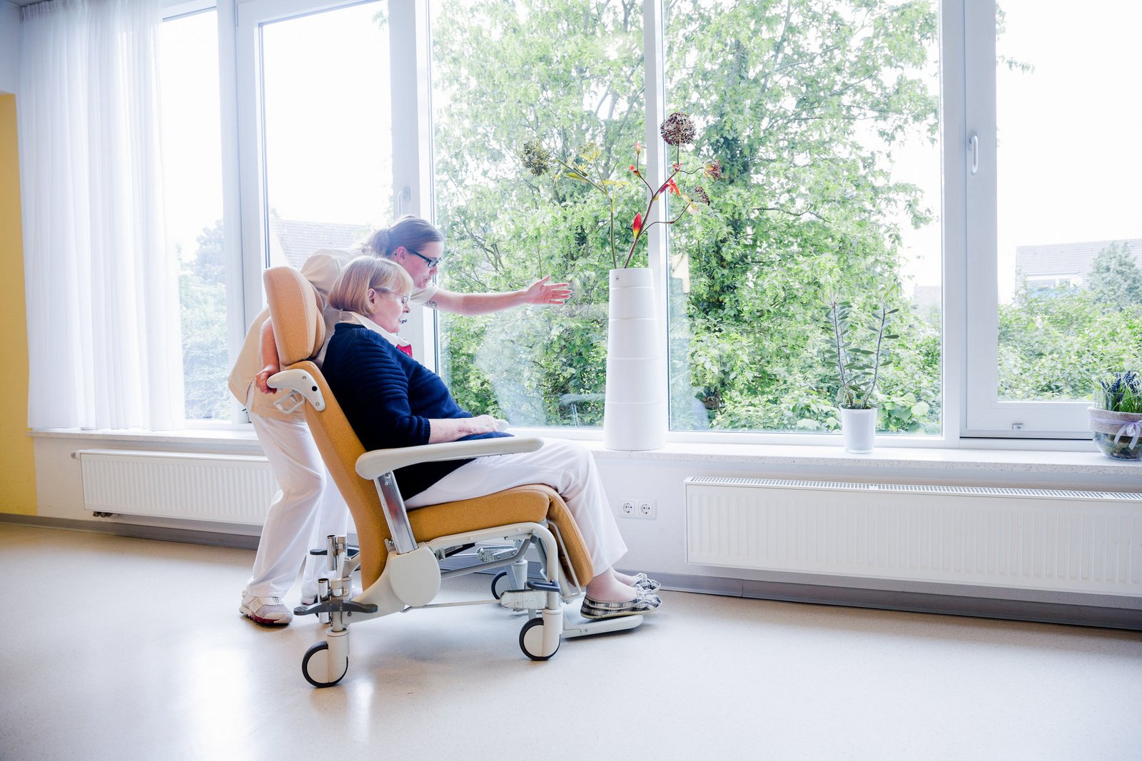 Pflegerin und Patientin im Gespräch mit Blick in den Garten